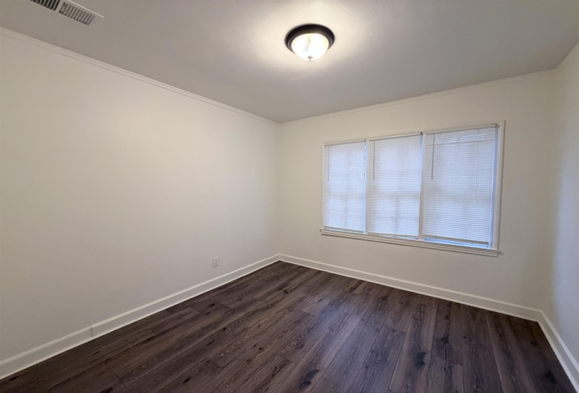 Empty room featuring dark wood-style flooring and ornamental molding