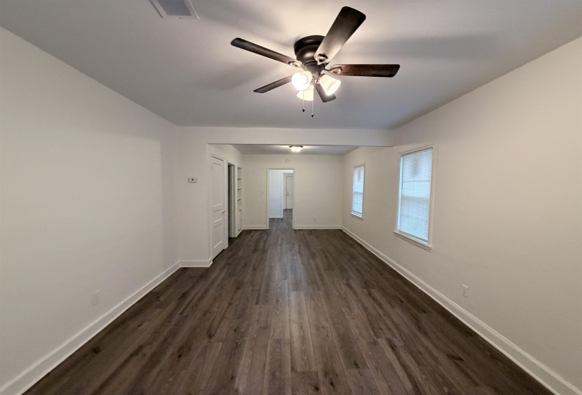 Unfurnished living room featuring dark wood-style flooring and ceiling fan