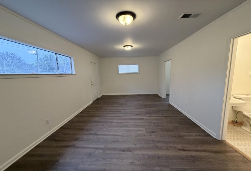 Unfurnished bedroom featuring dark wood-style floors, multiple windows, and ornamental molding