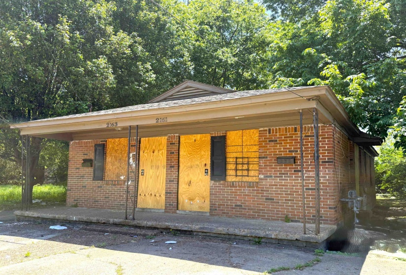 Brick facade property featuring a full-width covered porch with metal support columns and a shallow-pitched roofline