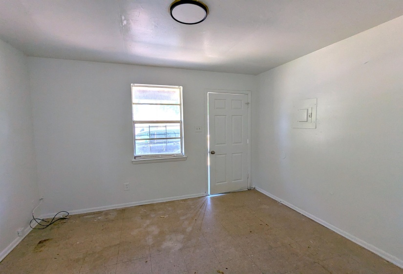 Interior room featuring a white paneled door, a single window, and a ceiling-mounted light fixture