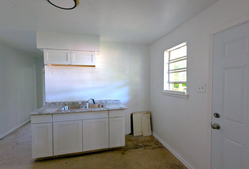 White cabinetry with a double basin stainless steel sink and a speckled countertop