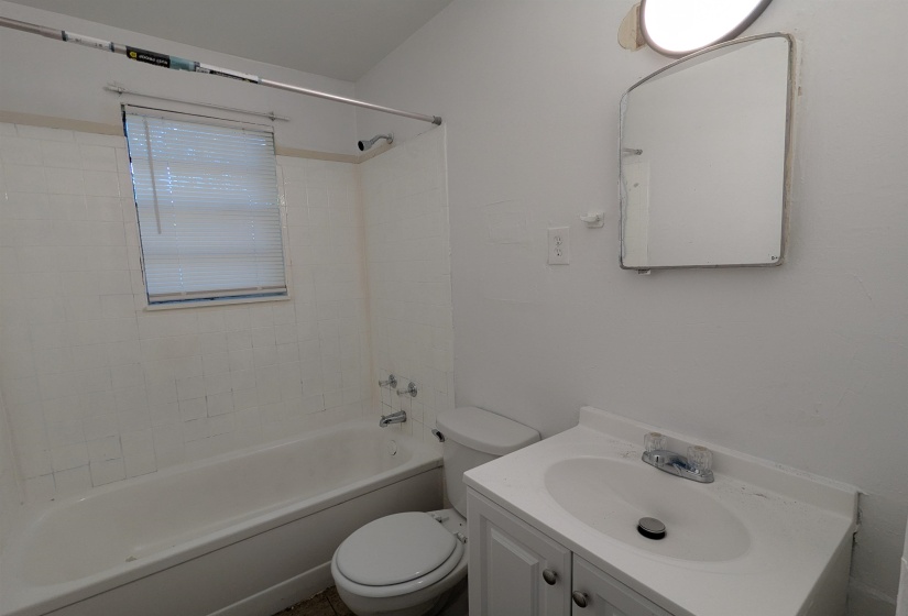 Bathroom featuring a white bathtub, ceramic tile surround, white vanity with integrated sink, and an illuminated mirror