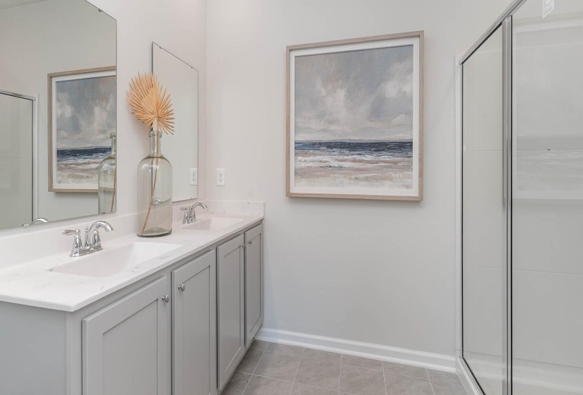 Full bath with double vanity, a stall shower, and light tile patterned floors