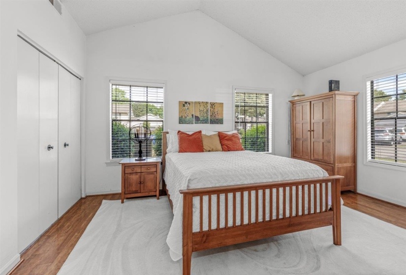 Bright room featuring a vaulted ceiling and wood-finish flooring