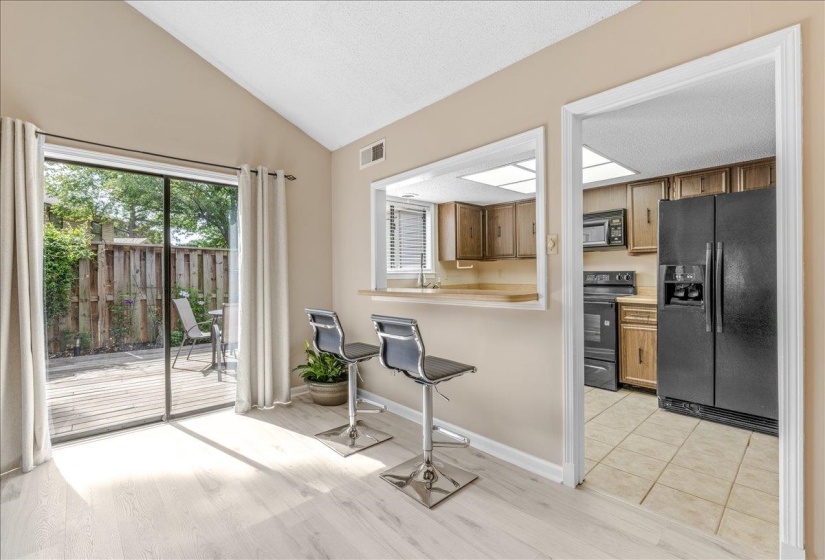 Sliding glass door opening to an outdoor deck area with privacy fencing