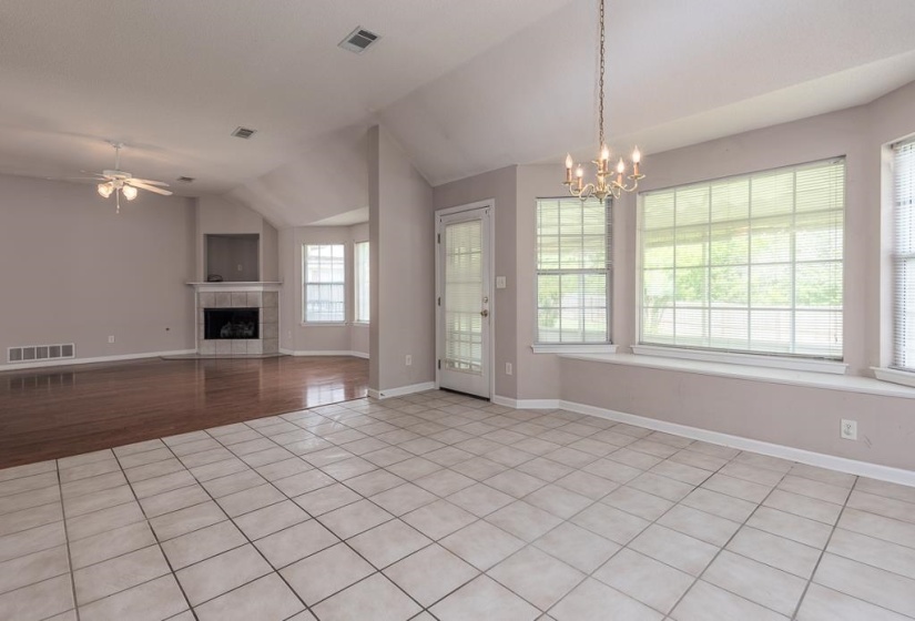 Spacious room featuring large bay windows with integrated sill, a classic chandelier, and durable tile flooring