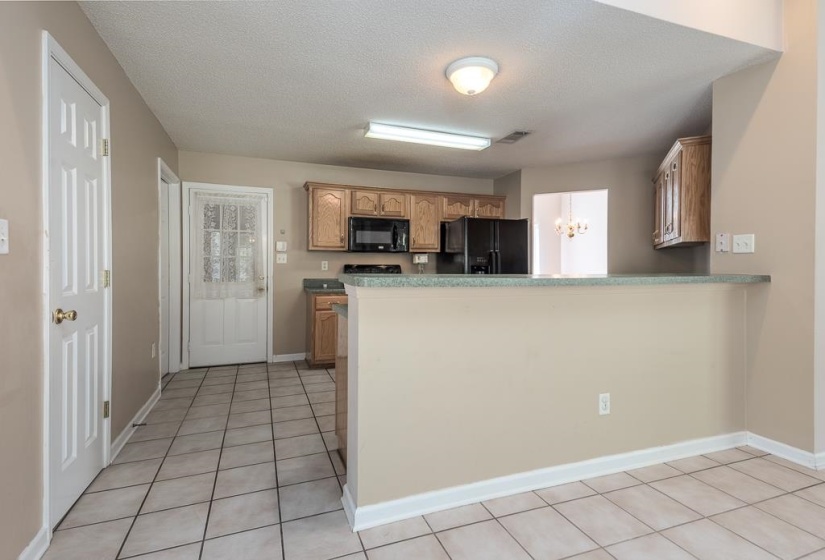 Kitchen featuring light wood-finish cabinetry, black appliances, and a breakfast bar with a speckled countertop