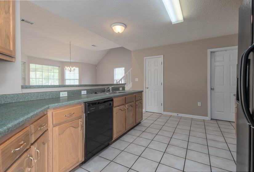Kitchen featuring wood cabinetry, green countertops, and a black dishwasher