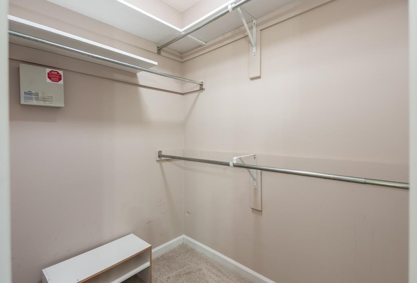 Walk-in closet featuring carpet flooring, multiple shelving units, and metal hanging rods