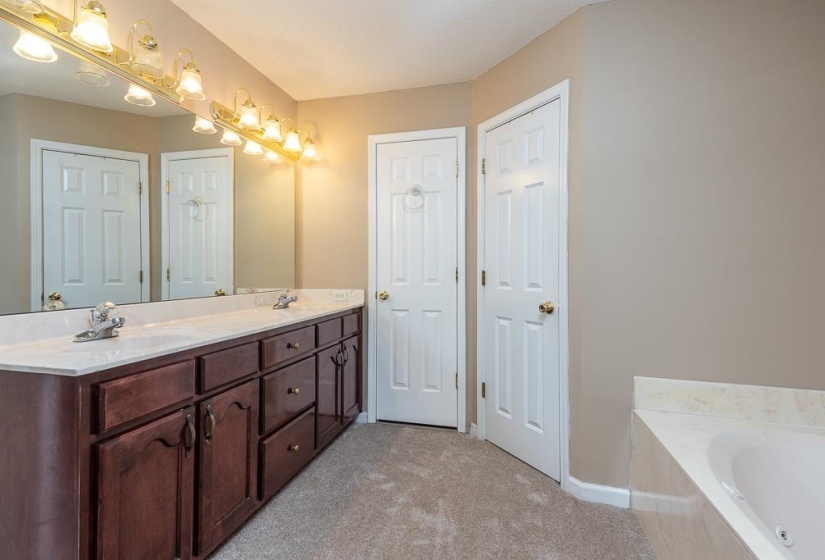 Bathroom featuring a double vanity with cherry-toned cabinetry, a white countertop, dual sinks, and a large mirror with overhead lighting