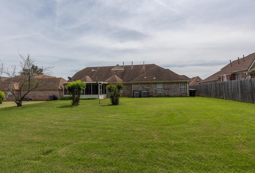 Expansive rear lawn featuring a privacy fence