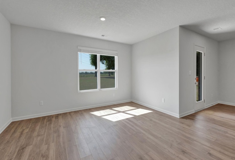 Spacious room featuring wood-finish flooring, white baseboards, and neutral wall paint