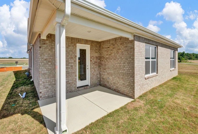 Covered patio with a concrete slab, brick exterior, and white framed glass panel door