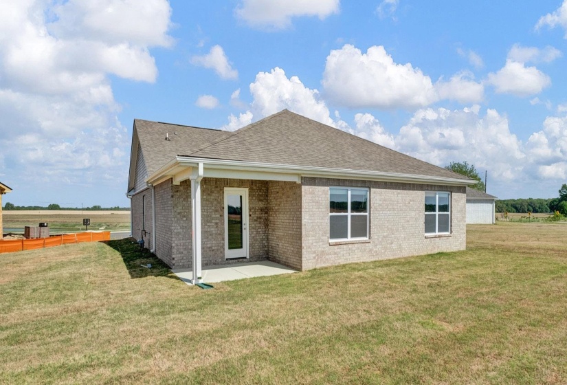 Rear exterior featuring a covered patio, light-colored brick facade, and multiple windows