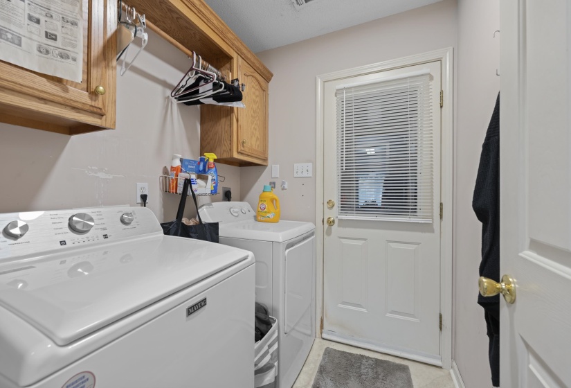 Laundry area featuring wood-finish cabinetry, a white exterior door with integrated blinds, and light-toned walls