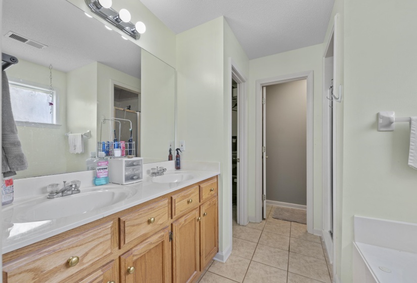 Dual vanity with wood-finish cabinetry, integrated sinks, and polished chrome fixtures