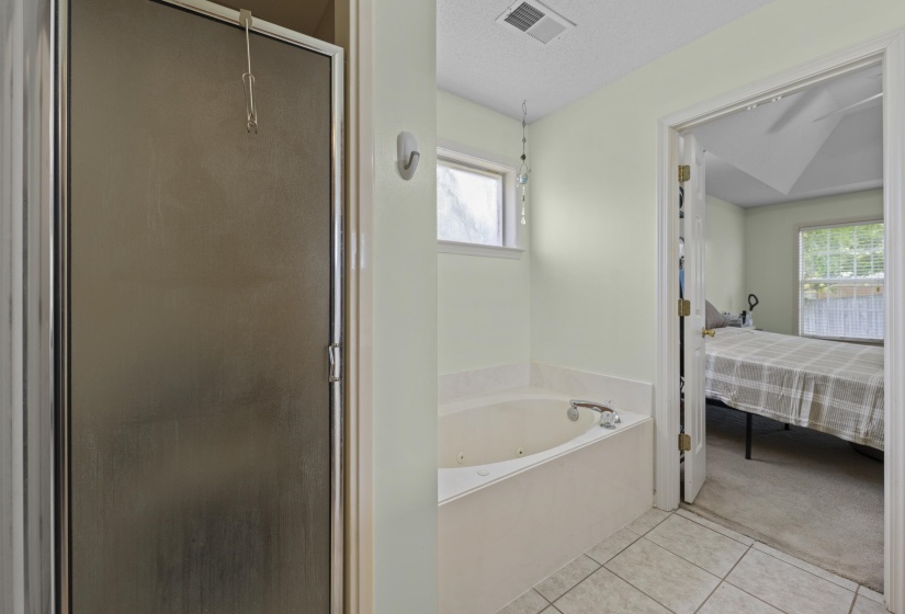 Bathroom featuring a built-in tub, tiled flooring, and a glass-enclosed shower