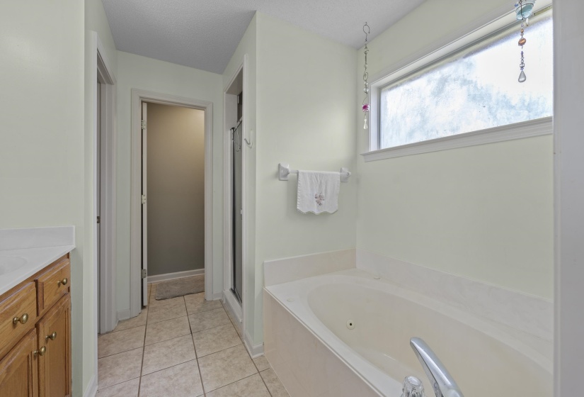 Bathroom featuring a built-in soaking tub, tiled flooring, wood-finish cabinetry, and a frosted transom window