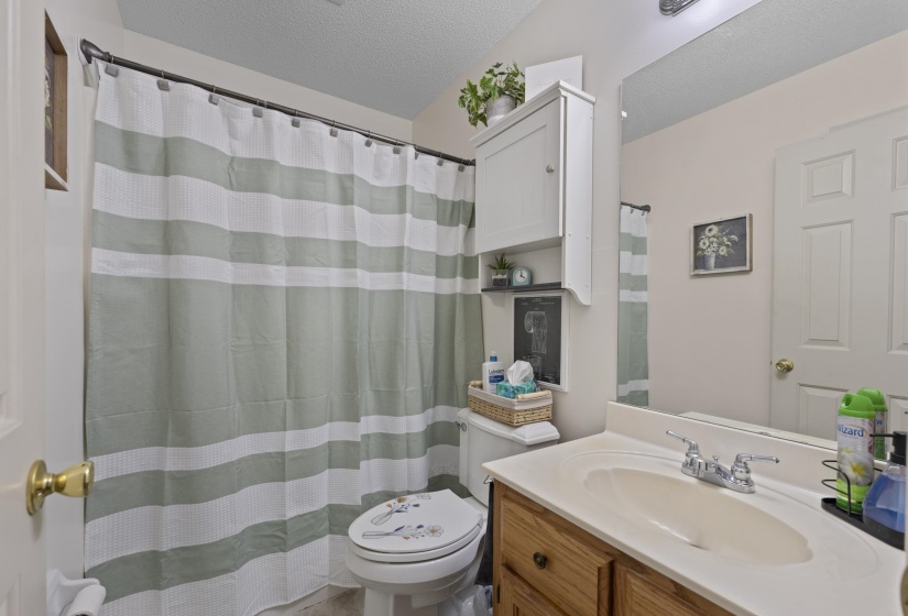Bathroom featuring a wood-finish vanity with an integrated sink, a large wall-mounted mirror, and overhead cabinet storage
