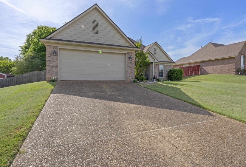 Exterior featuring a two-car garage, brick facade, gabled roofline, and a concrete driveway