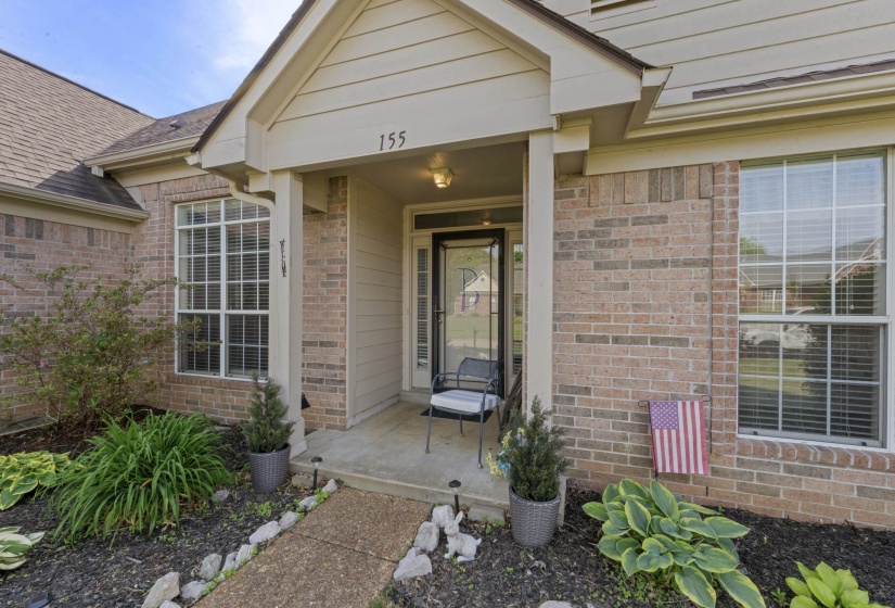 Brick exterior featuring a covered entry, transom window, and a concrete porch