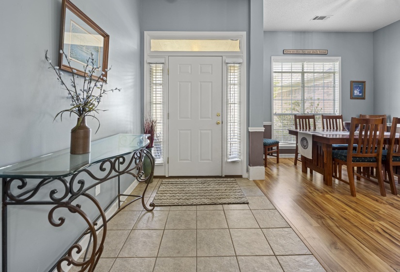Entryway featuring a white paneled door with sidelights and transom window, tile flooring, and light blue wall color