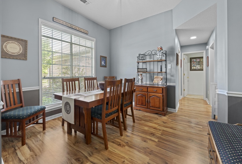 Spacious room featuring wood-finish flooring, a large window with blinds, and two-tone wall paint with wainscoting