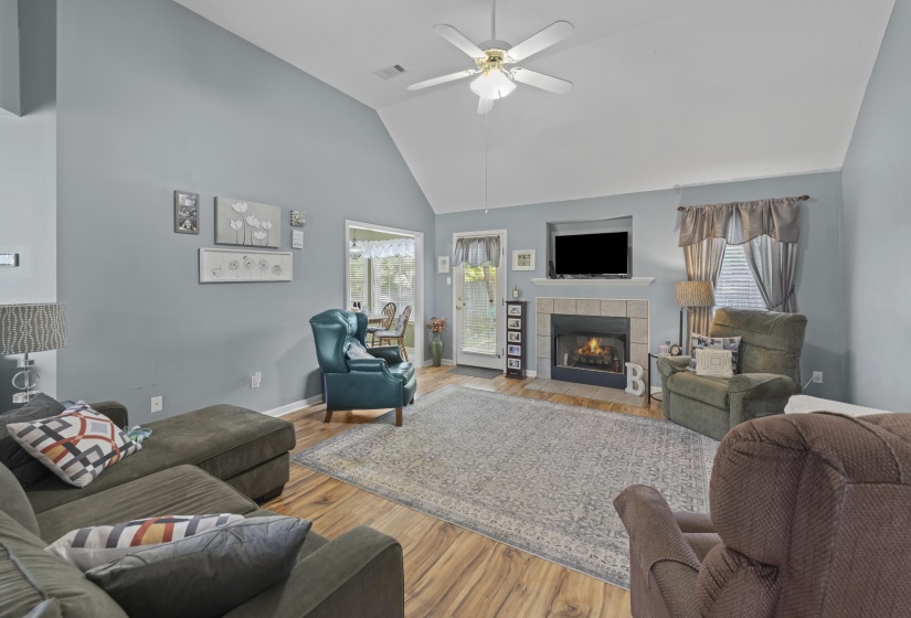Vaulted ceiling living area featuring wood-finish flooring and a tiled fireplace surround