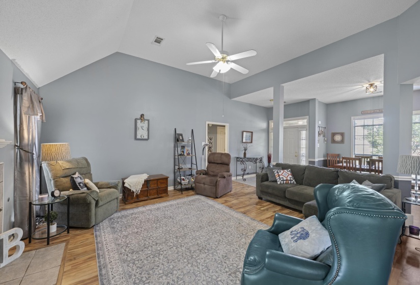 Spacious living area featuring a vaulted ceiling and wood-finish flooring
