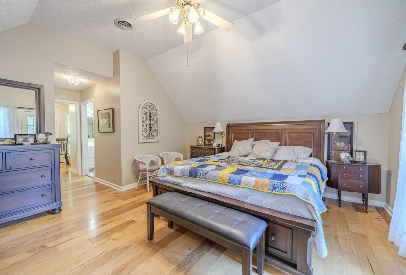 Spacious room featuring wood-finish flooring, an angled ceiling, and a ceiling fan with integrated lighting