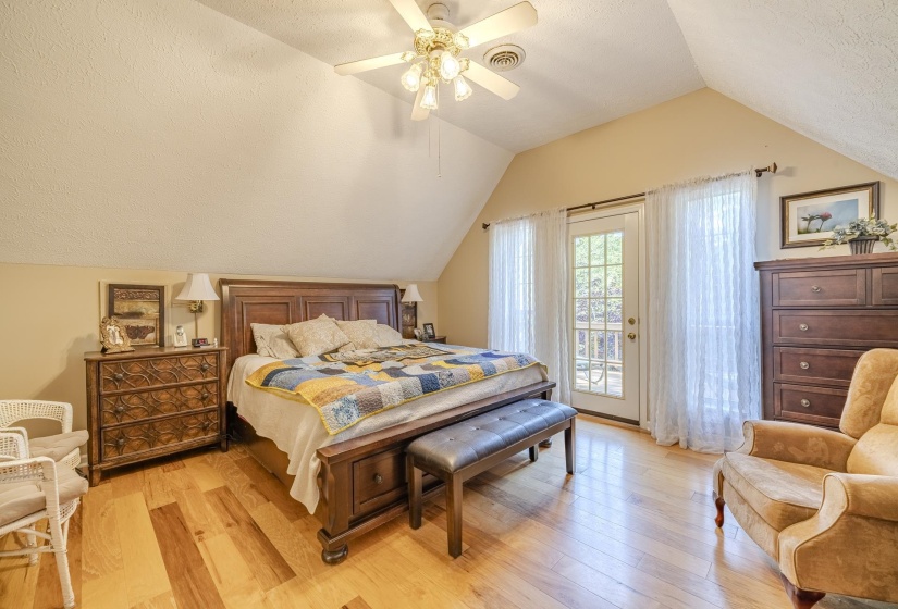 Bedroom featuring wood-finish flooring, a ceiling fan with integrated lighting, and a French door with transom windows
