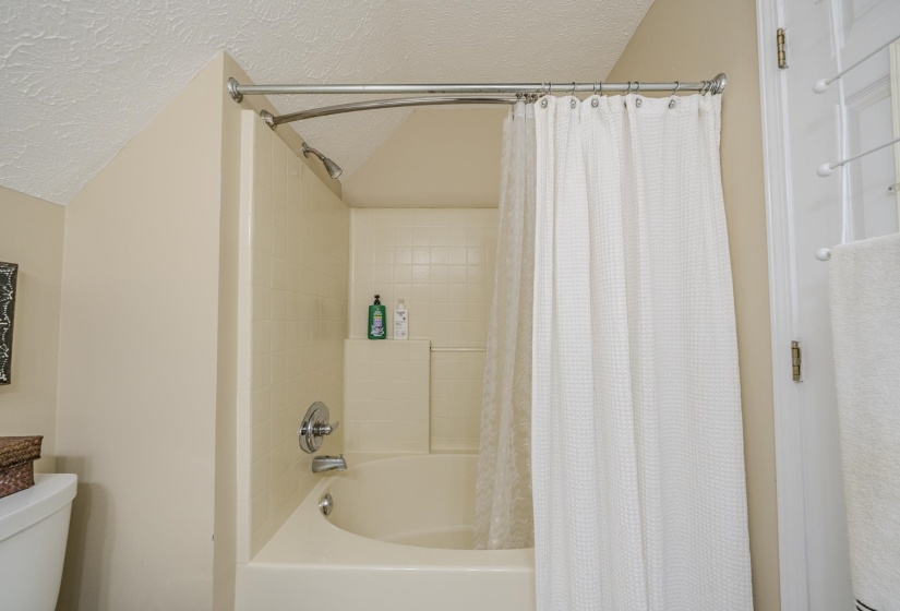 Bathtub and shower combination featuring a tiled surround and chrome fixtures