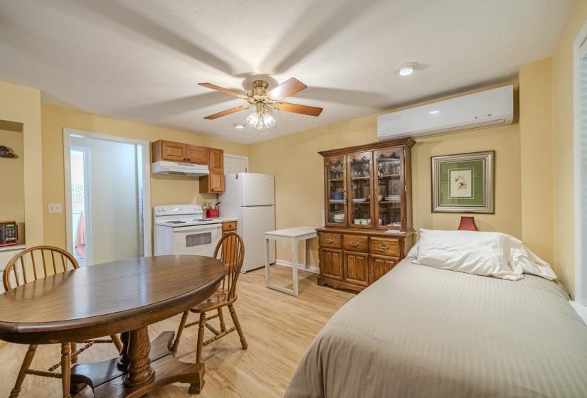 Open-concept living space featuring wood-finish flooring, a ceiling fan with integrated lighting, recessed lighting, a mini-split air conditioning unit, and a kitchen area with wood cabinetry and white appliances