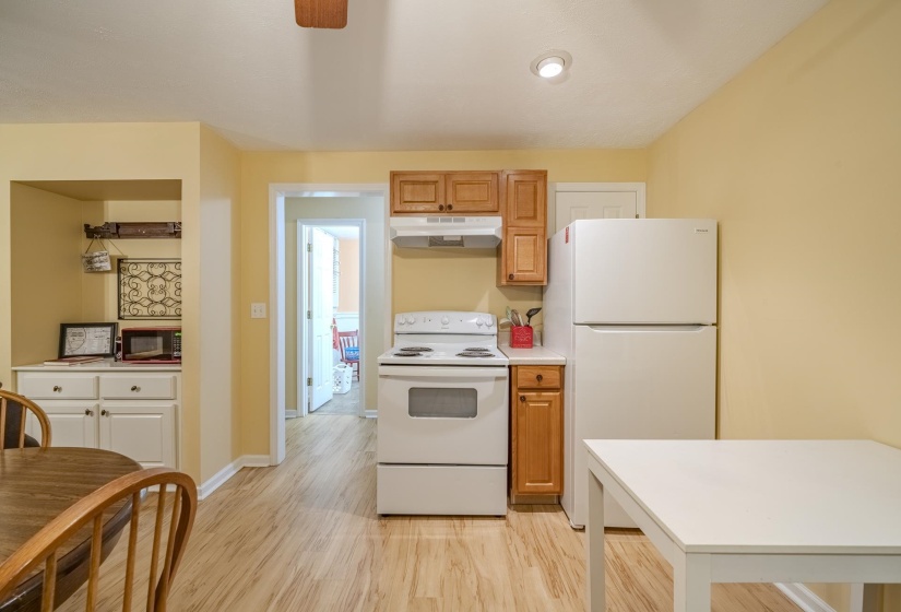 Kitchen area featuring wood-finish flooring, white appliances, and a built-in cabinet with a countertop