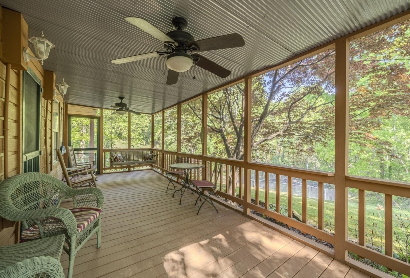 Screened porch featuring a corrugated metal ceiling, wood-finish flooring, and two ceiling fans with integrated lighting