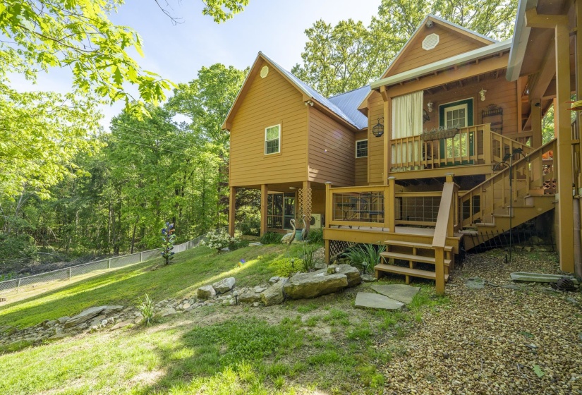 Multi-level wood deck featuring a covered porch, outdoor stairs, and gravel landscaping