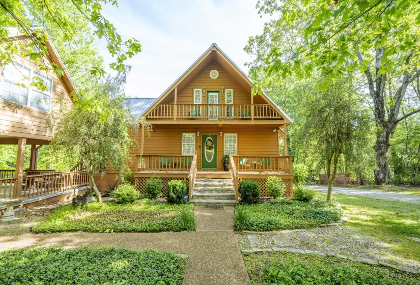 Wood-sided home featuring a front balcony, covered porch, and mature landscaping