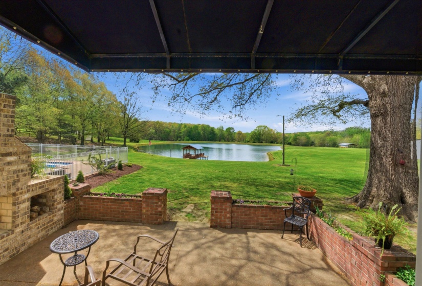 Covered patio with a brick fireplace and concrete flooring