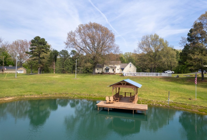 Private pond with a covered dock structure featuring a pitched roof and wood-finish decking