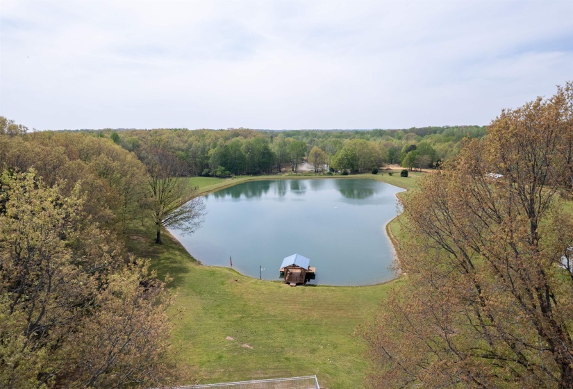 Expansive private pond surrounded by lush green lawn and mature trees