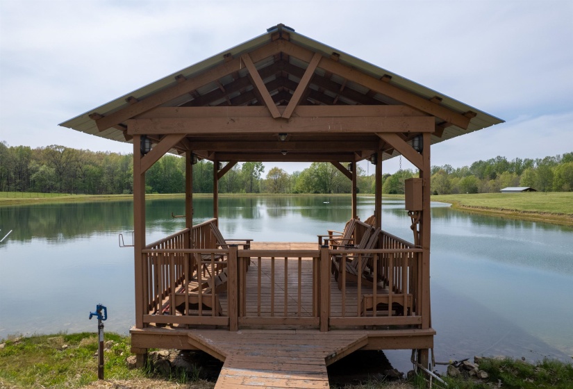 Wood-frame gazebo with a metal roof extending over a body of water