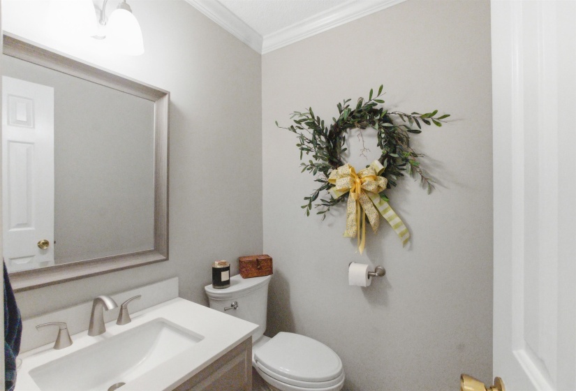 Powder room featuring a white single-basin vanity with a brushed nickel faucet, a framed mirror, and a white toilet