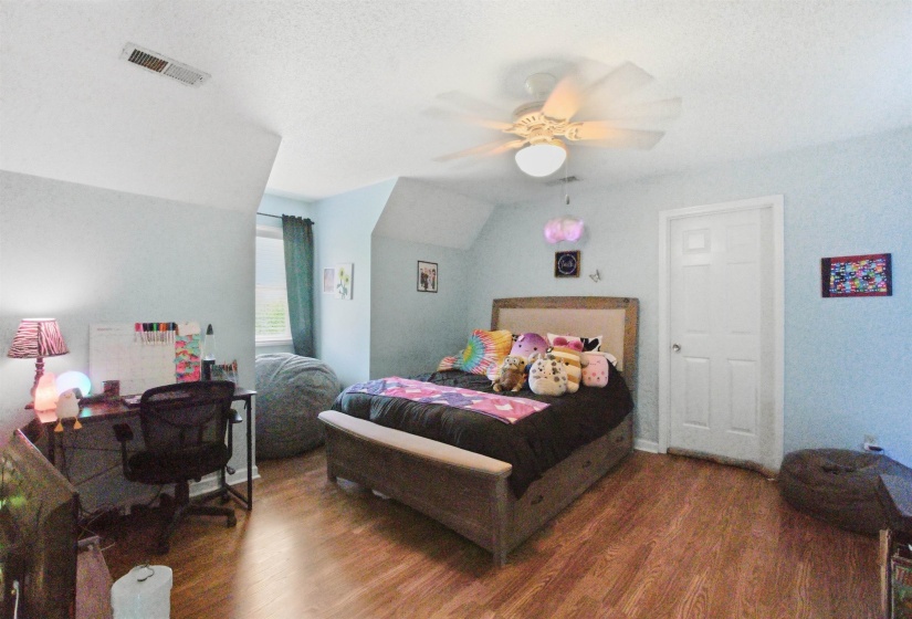 Room featuring wood-finish flooring, a neutral wall color, and an angled ceiling line