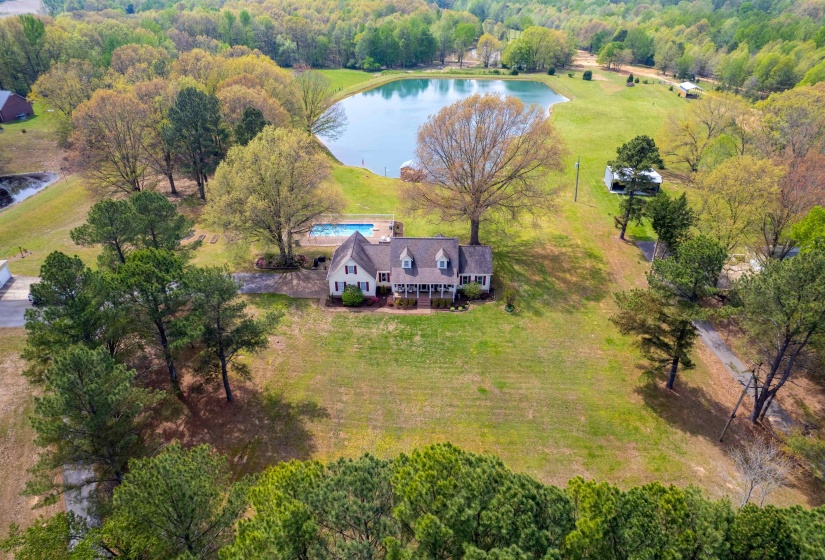 Expansive property featuring a single-family residence, a freshwater pond, an inground swimming pool, mature trees, and open green spaces