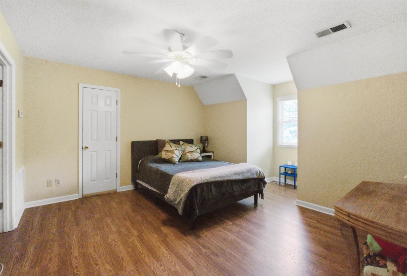 Spacious room featuring wood-finish flooring, light-toned walls, and a ceiling fan with integrated lighting