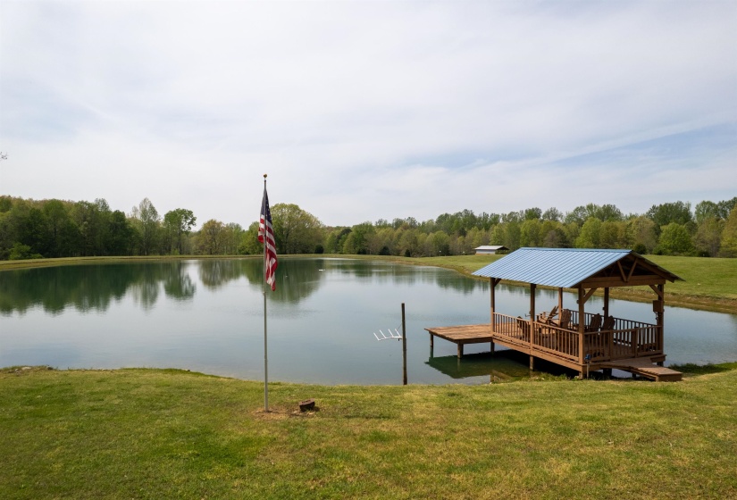 Expansive pond with a covered dock featuring a blue metal roof and a wooden frame
