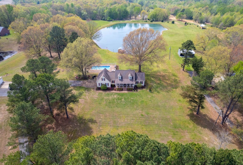 Expansive property featuring a two-story residence with dormer windows, a front porch, and a swimming pool