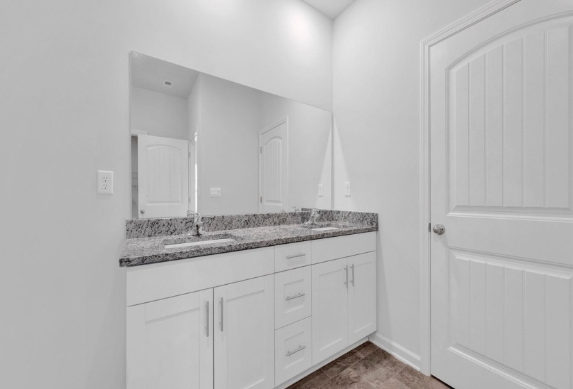 Dual vanity with granite countertop, integrated sinks, white cabinetry, and brushed nickel hardware