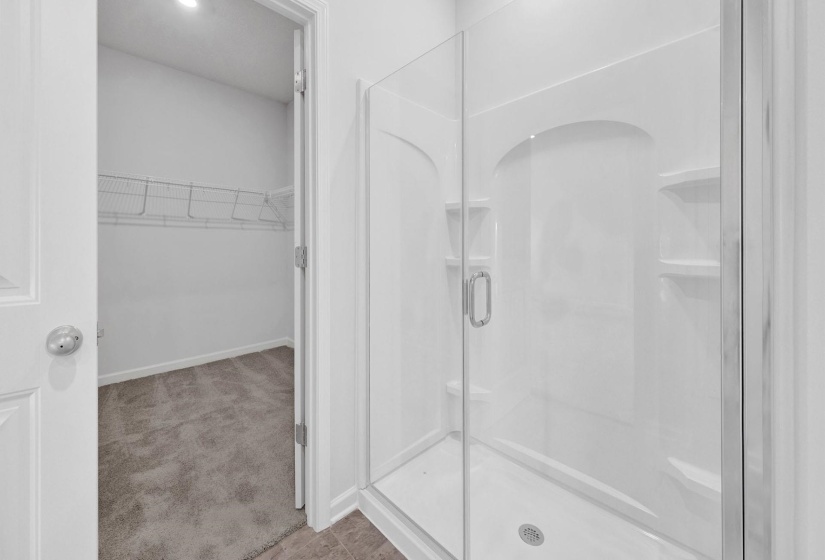 White-paneled shower with a clear glass enclosure and built-in shelving